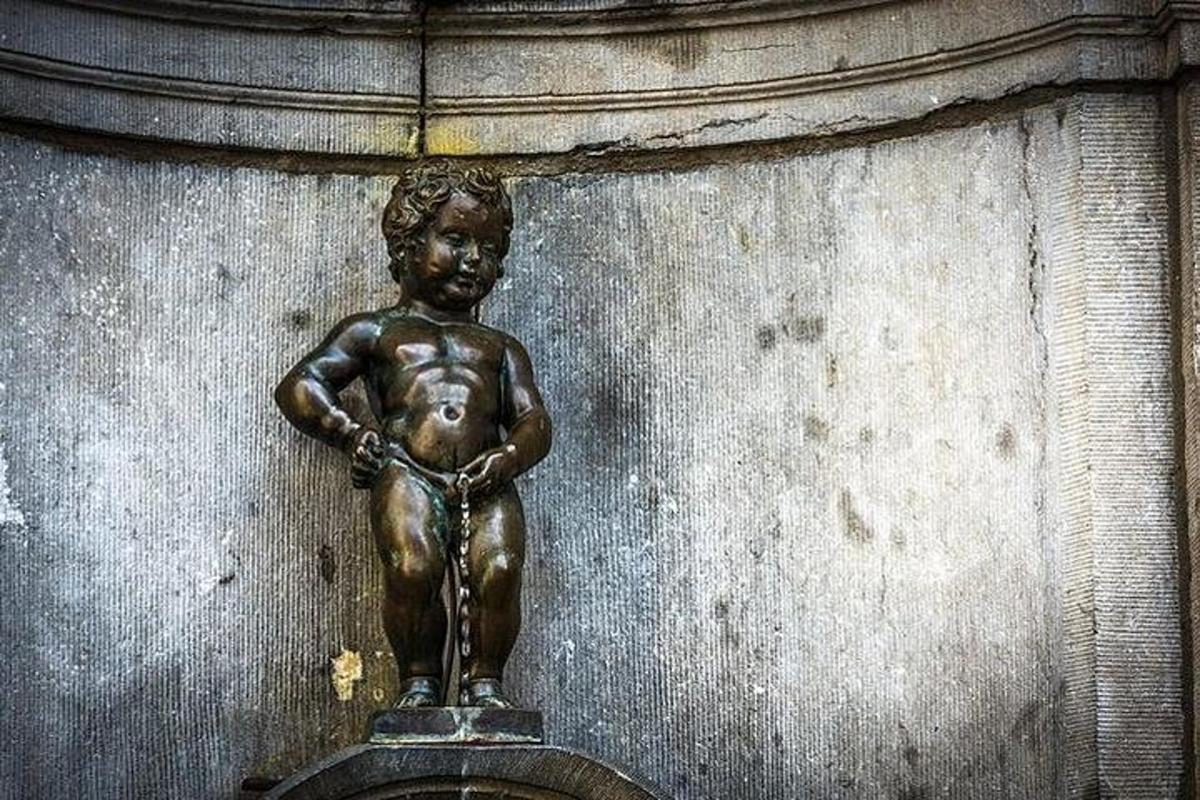 uma estátua de bronze de um menino em uma parede