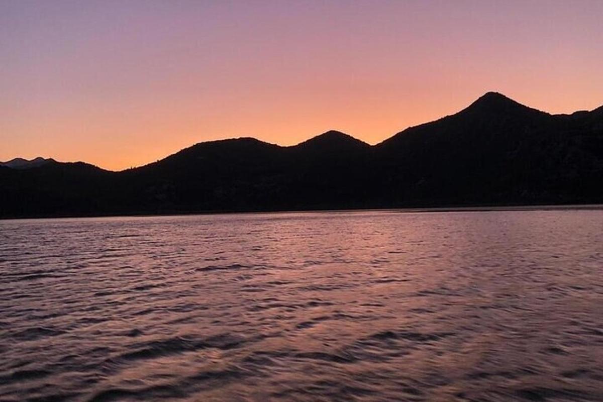 matahari terbenam di atas danau dengan pegunungan di latar belakang