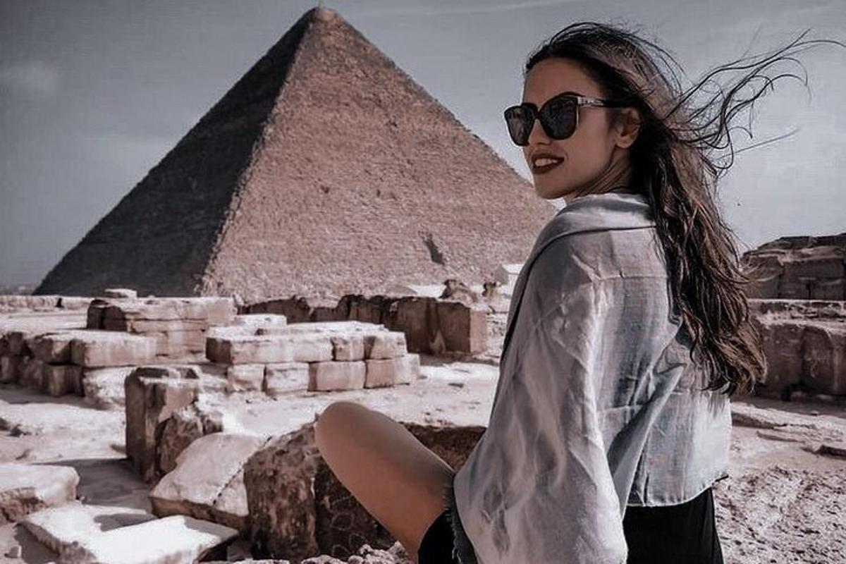 isang babaeng nakaupo sa isang bato sa harap ng pyramid