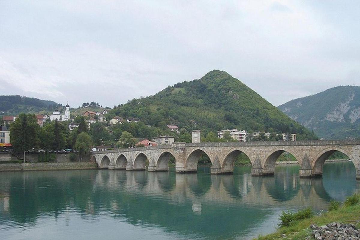 μια γέφυρα πάνω από ένα ποτάμι με βουνά στο φόντο