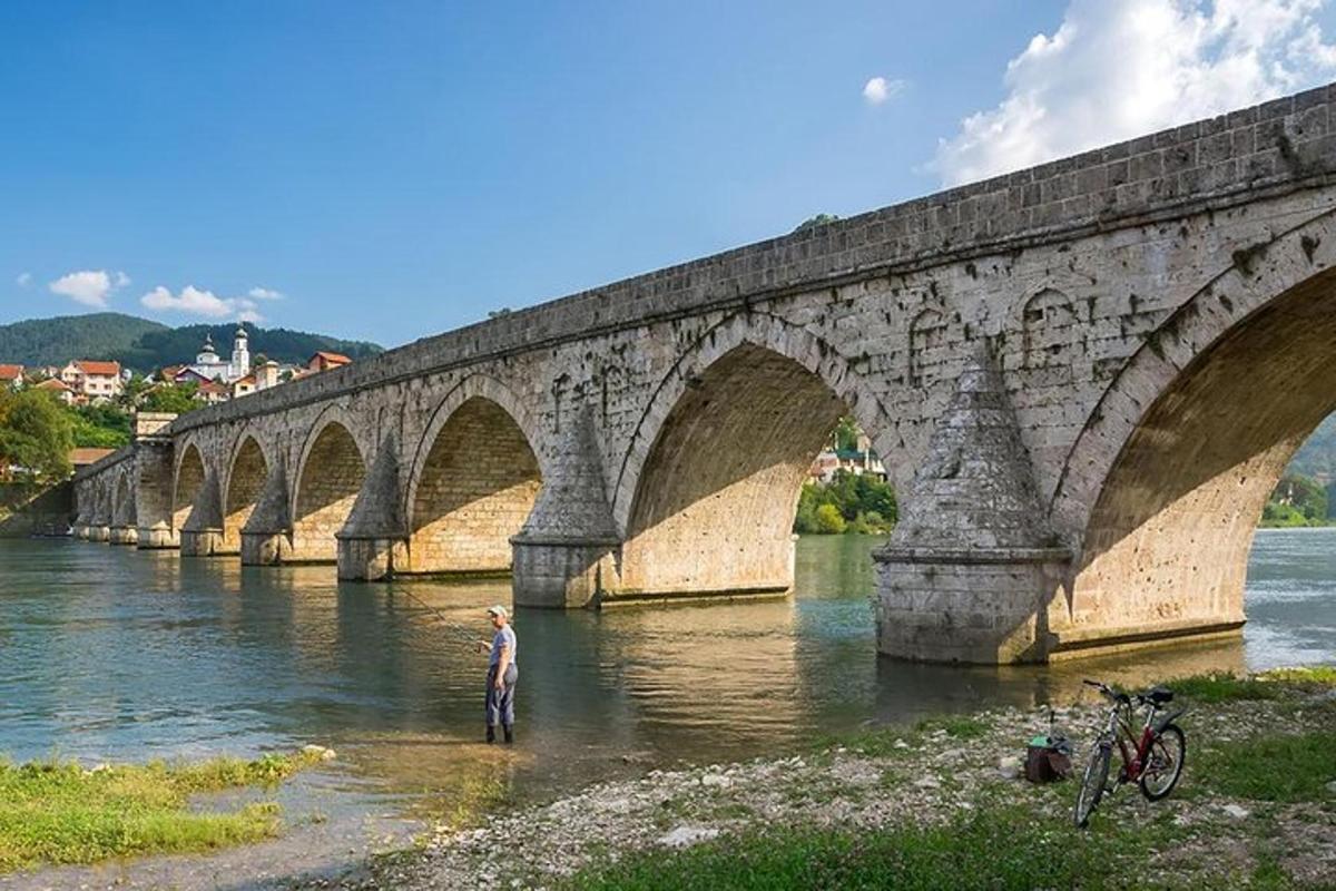 ένας άντρας που στέκεται στο νερό κάτω από μια γέφυρα