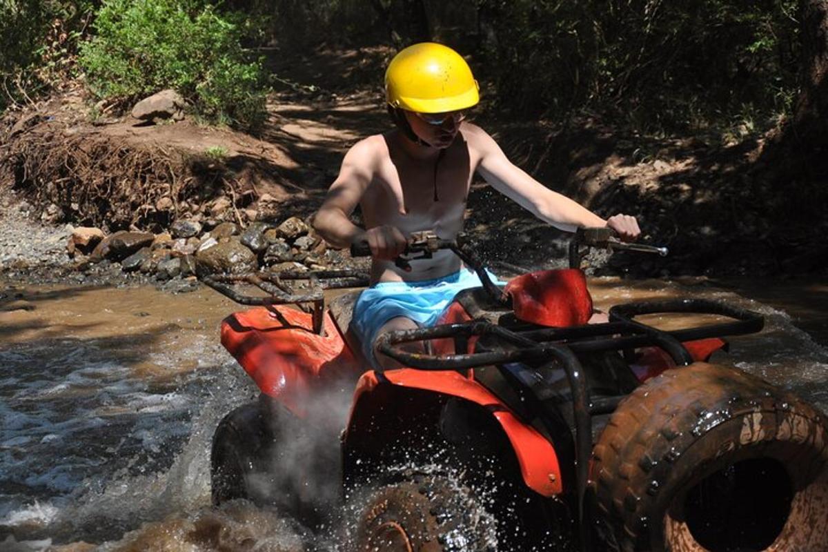 a man in a helmet on a atv in a river