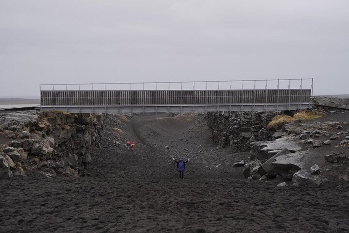 maður stendur á strönd undir brú