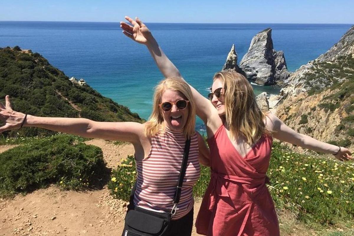 twee vrouwen staan op een berg met hun armen in de lucht