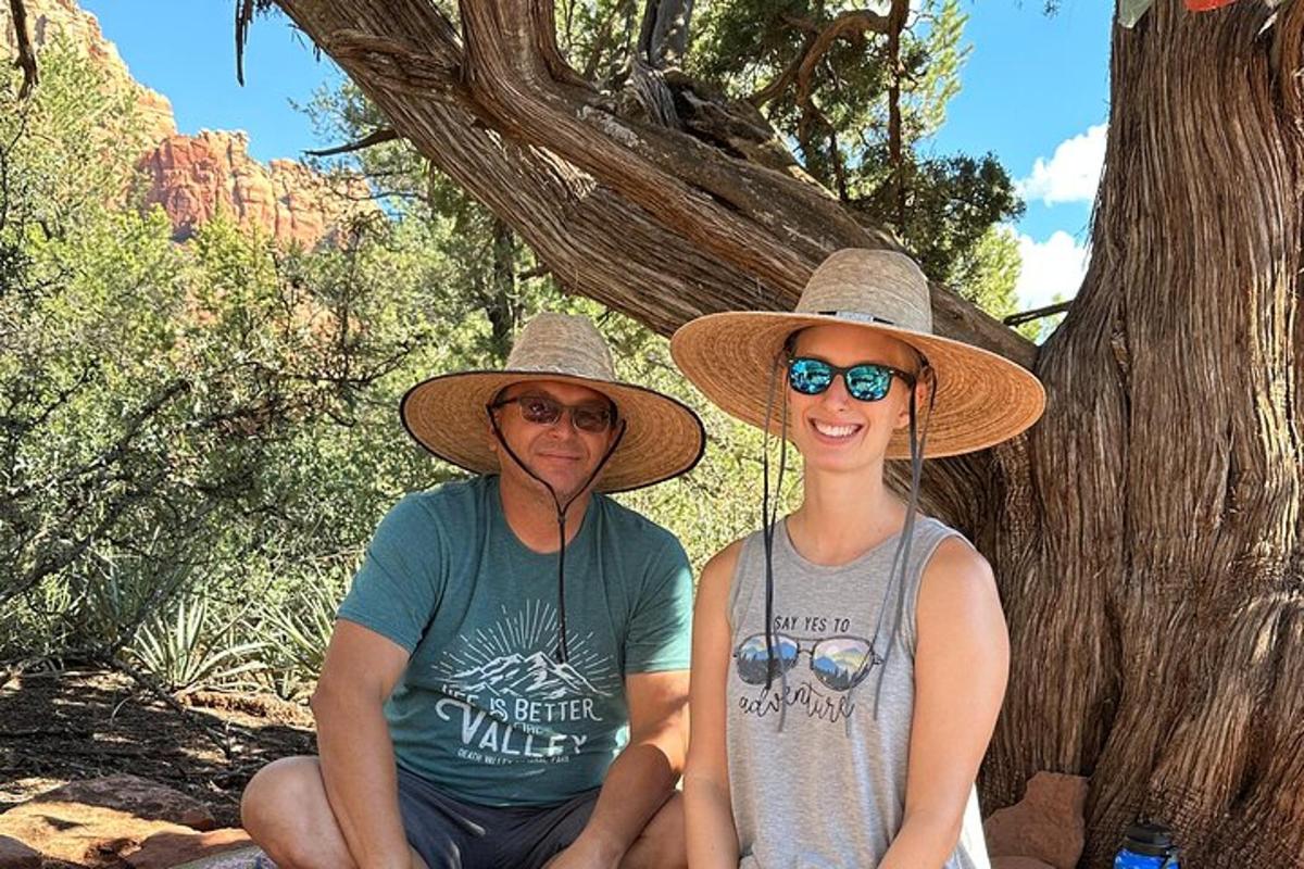 due persone che indossano cappelli sedute accanto a un albero