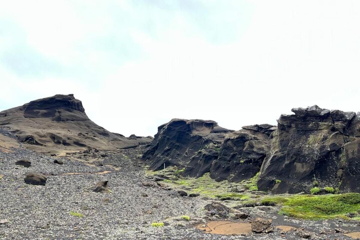 Una montaña rocosa con hierba a los lados.