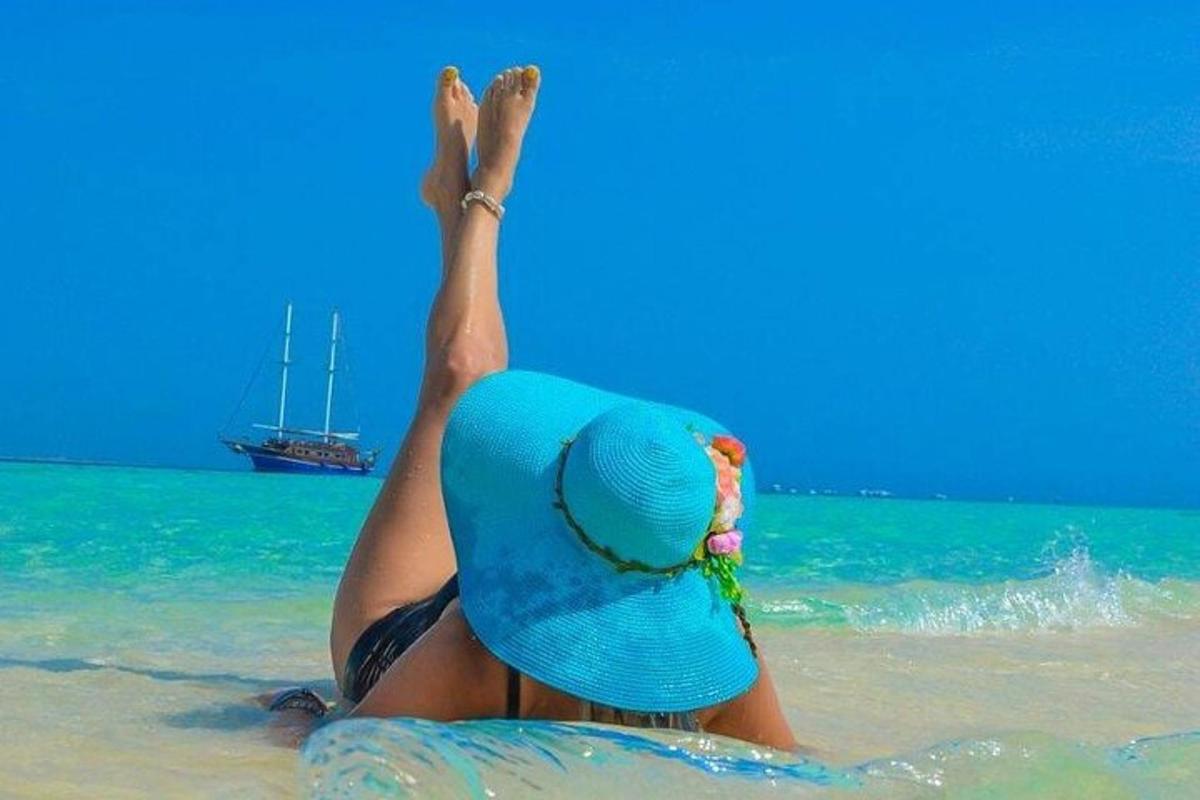 Una mujer tumbada en la playa con los pies en el agua