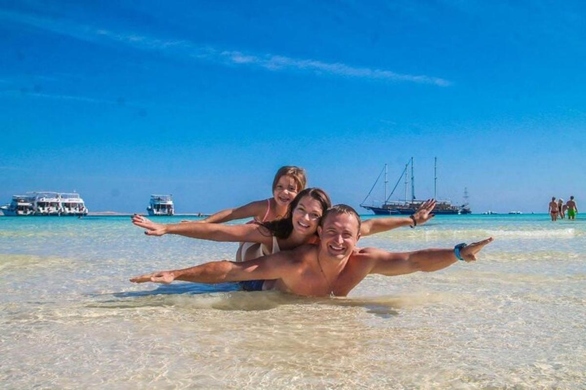 Tres personas tumbadas en el agua en una playa
