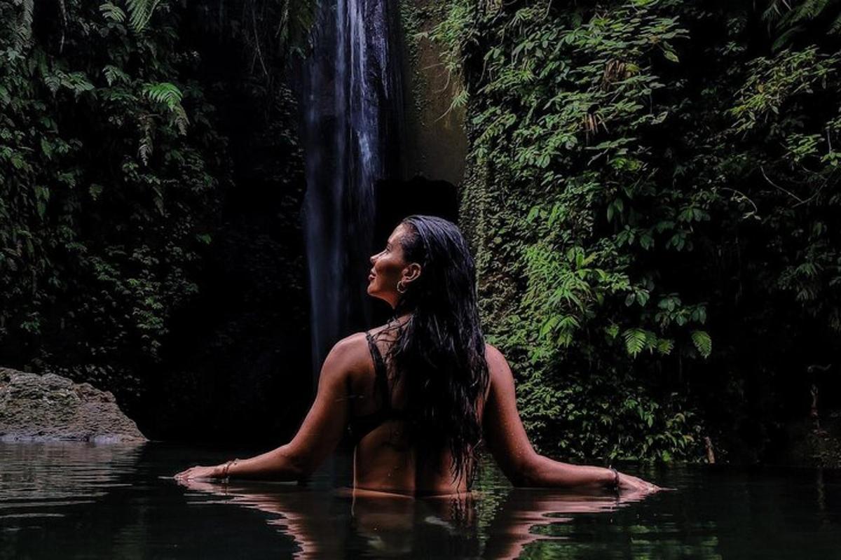 una donna seduta nell'acqua di fronte a una cascata