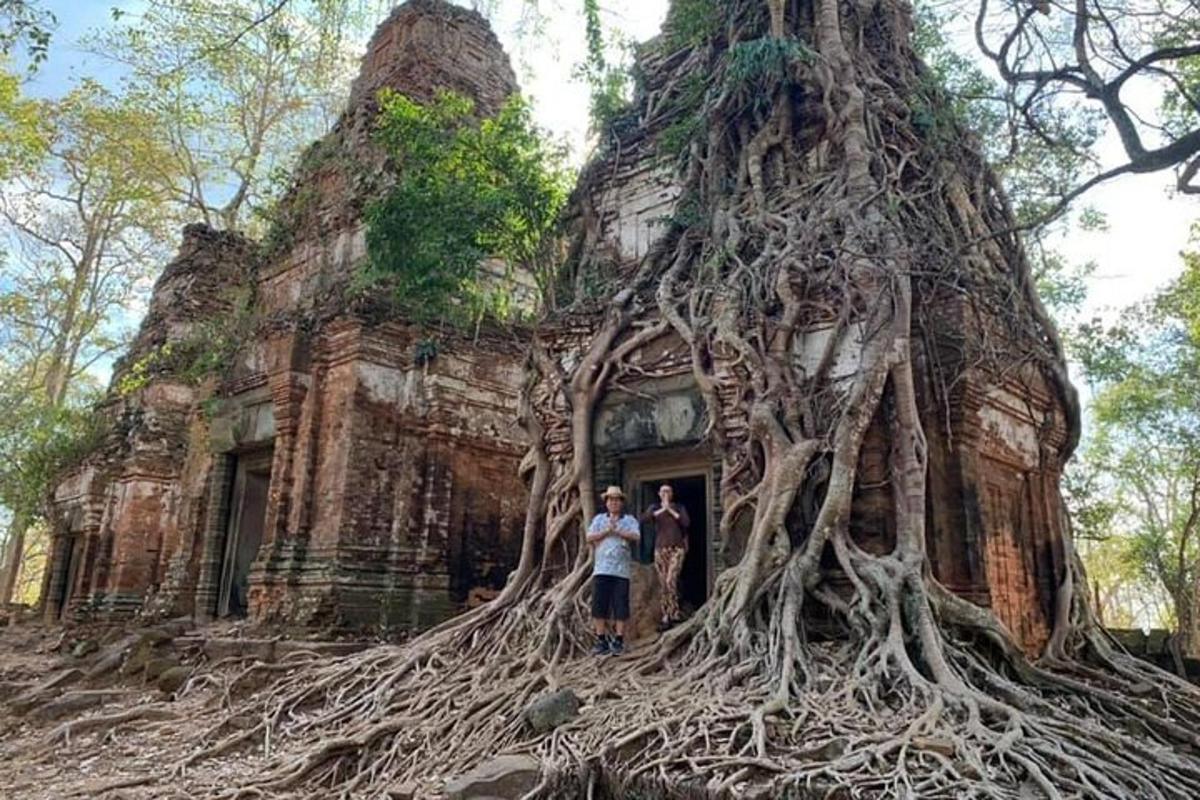 due persone in piedi davanti a un edificio con radici di albero