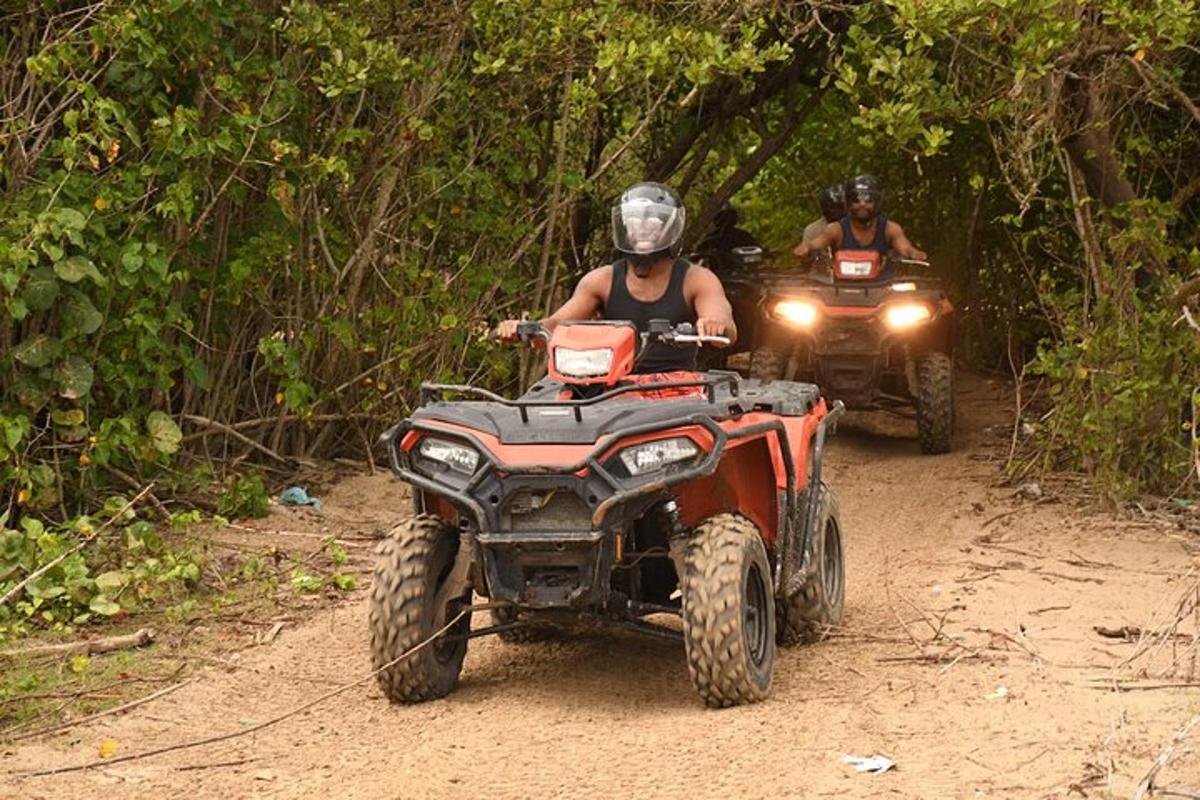 due persone che guidano un quad su una strada sterrata