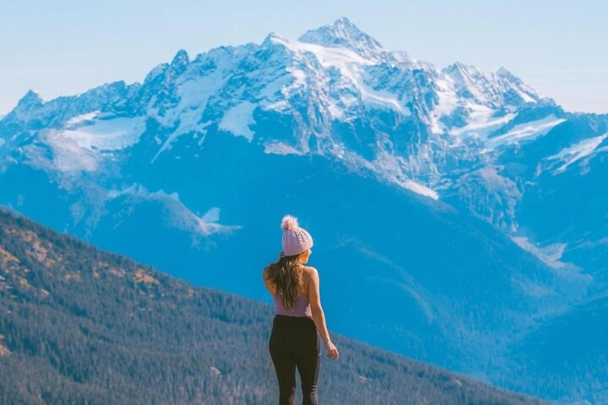 una donna in piedi sulla cima di una montagna che guarda un lago blu