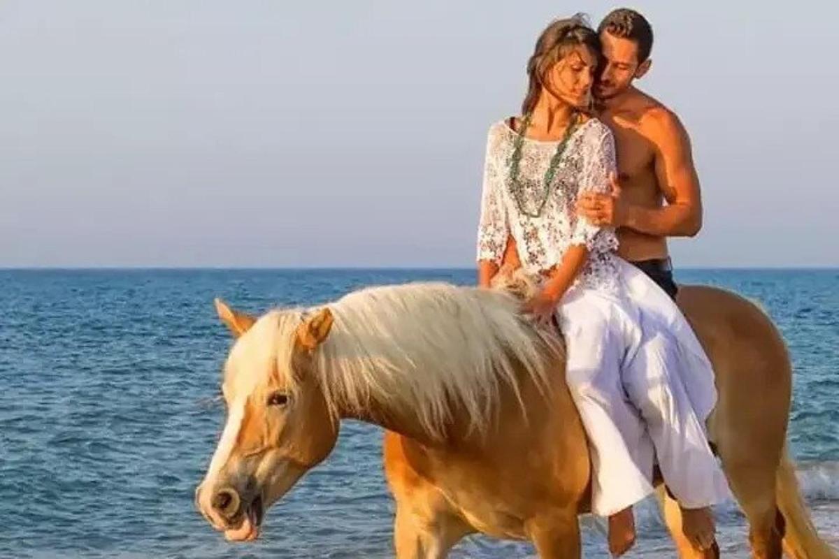 un home i una dona muntant a cavall a la platja