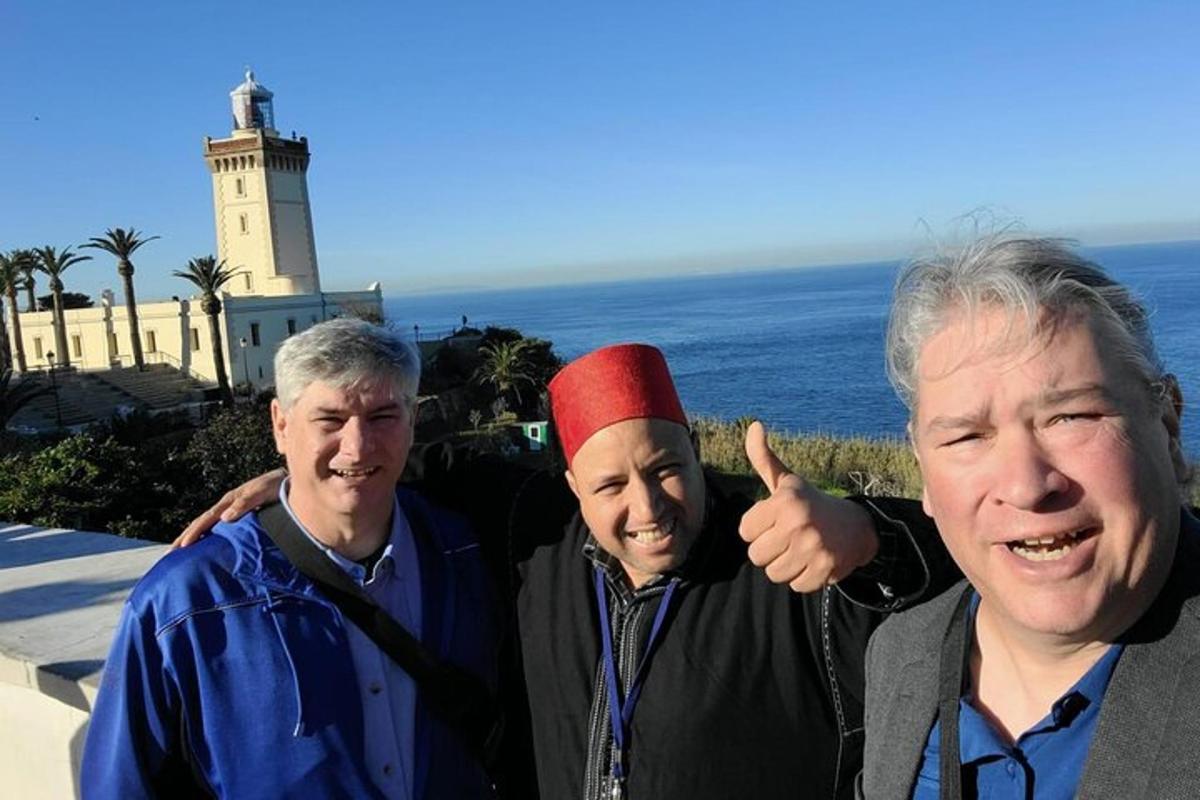 a group of three men standing in front of a lighthouse