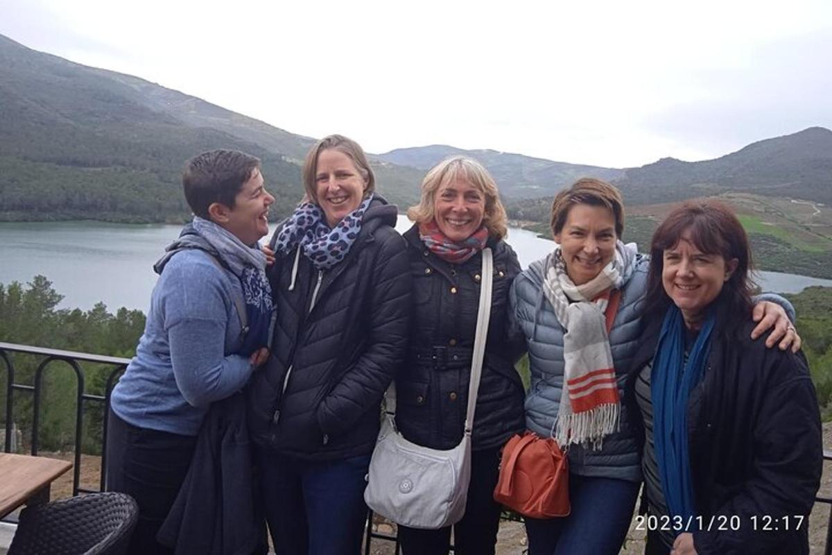 a group of women posing for a picture in front of a lake