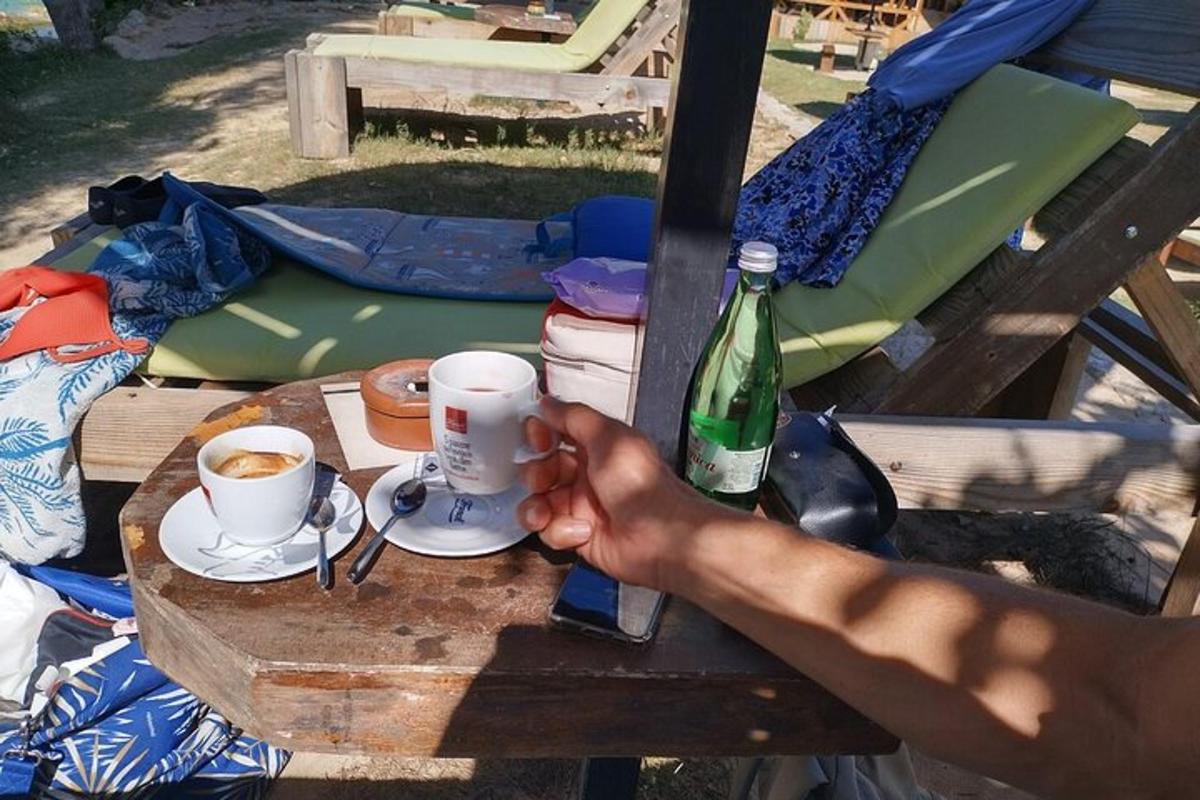 henkilö pitelee kahvikuppia piknikpöydällä