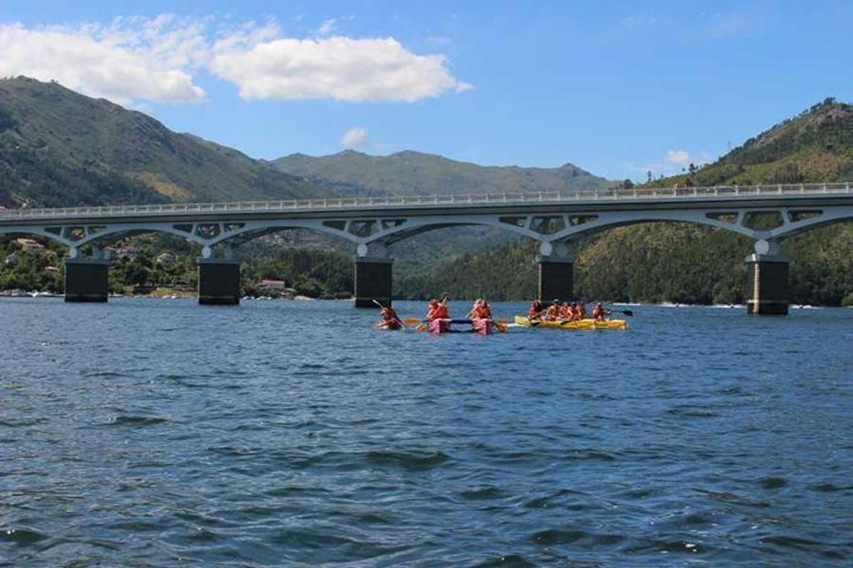 um grupo de pessoas em caiaques na água sob uma ponte