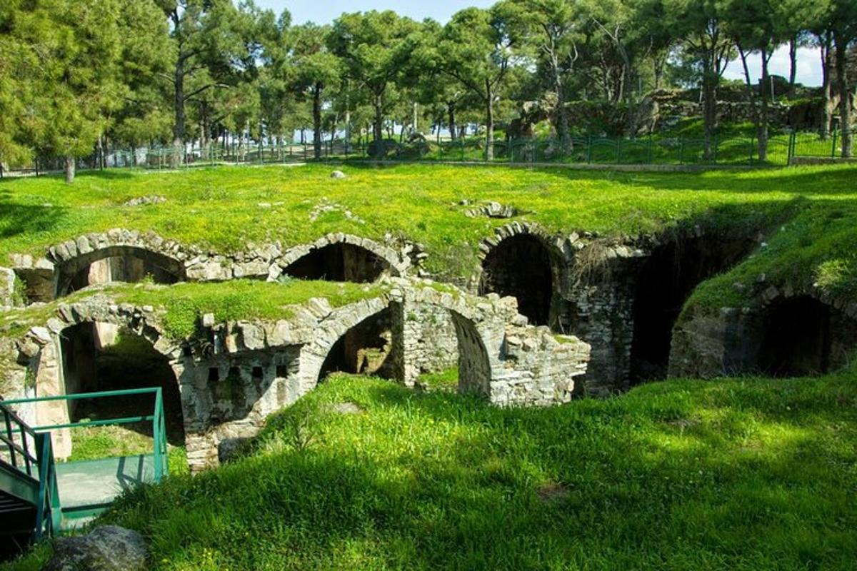 Un viejo puente de piedra en un campo con césped verde.