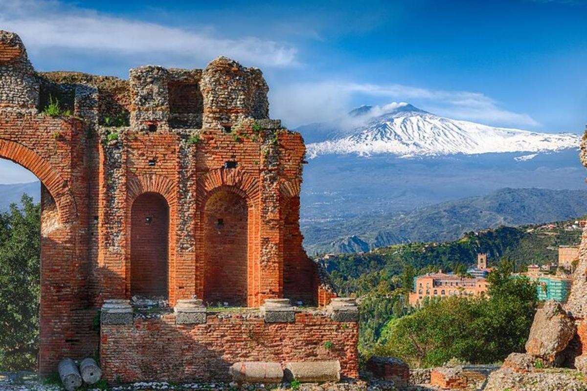 un vecchio edificio in mattoni con una montagna innevata sullo sfondo