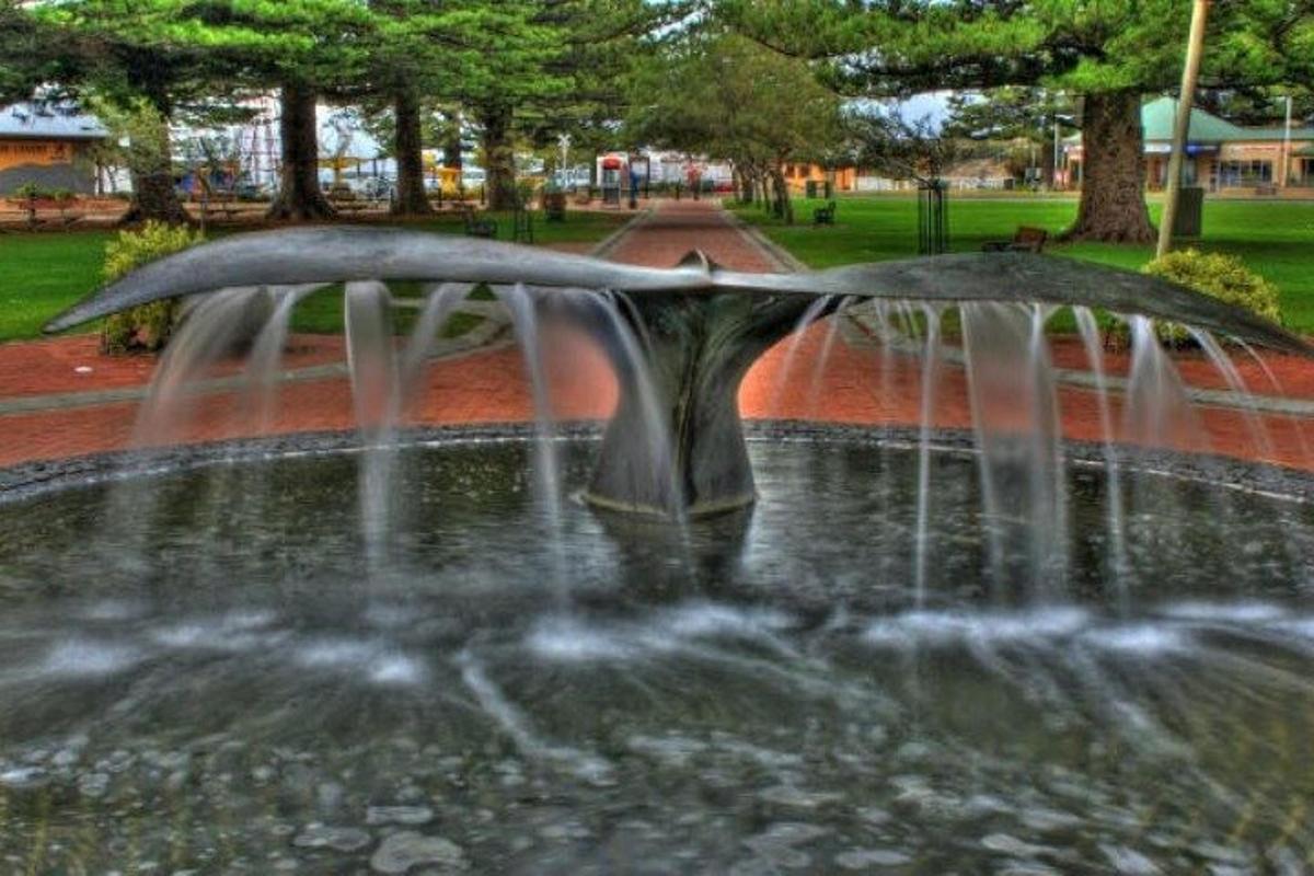 a water fountain in a park with a umbrella