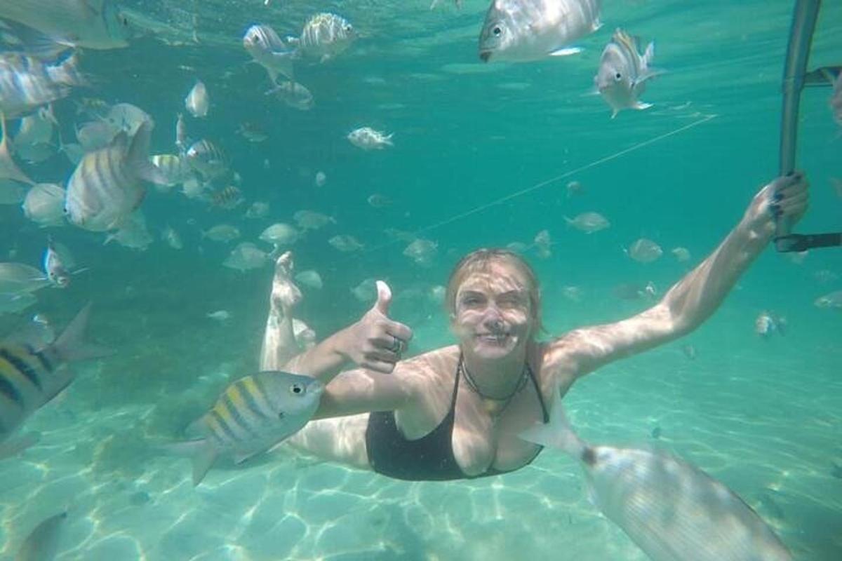 een man in het water die een vis omhoog houdt