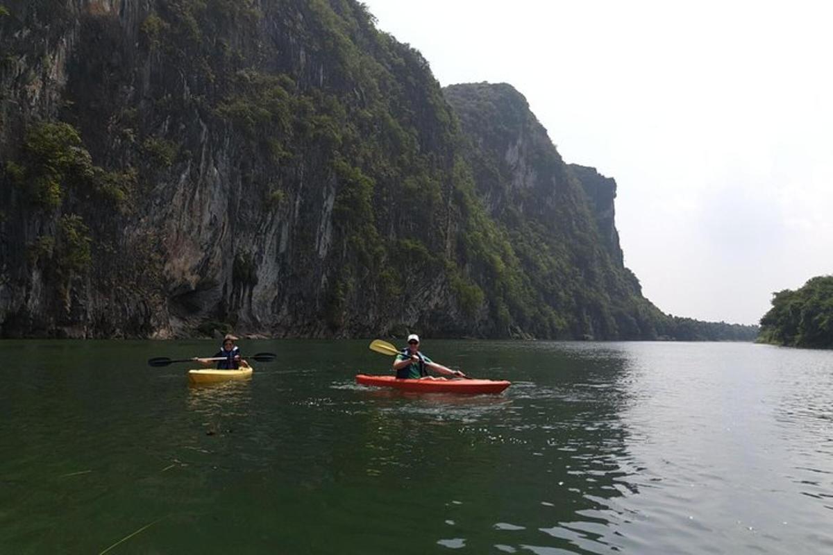 two people in kayaks on a lake near a mountain