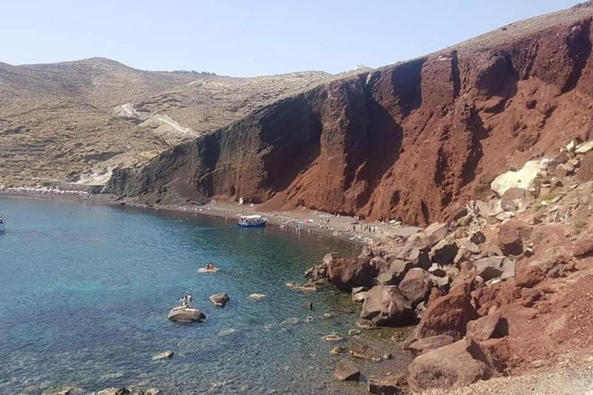 una platja amb gent a l'aigua al costat d'una muntanya