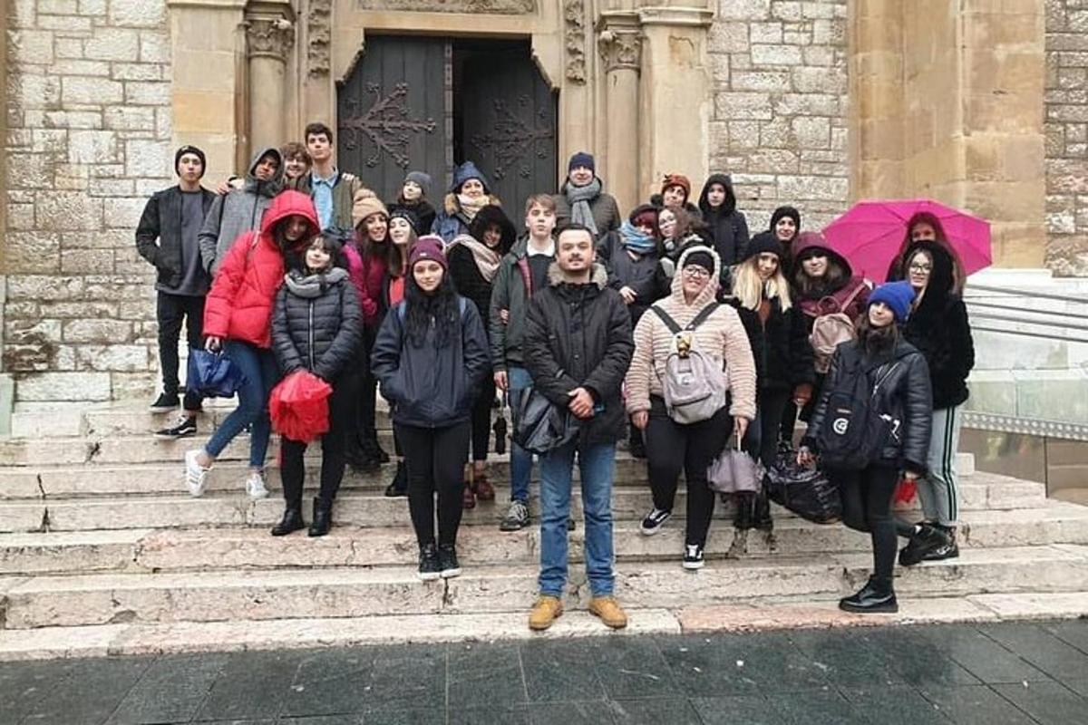um grupo de pessoas em pé nos degraus em frente a um prédio