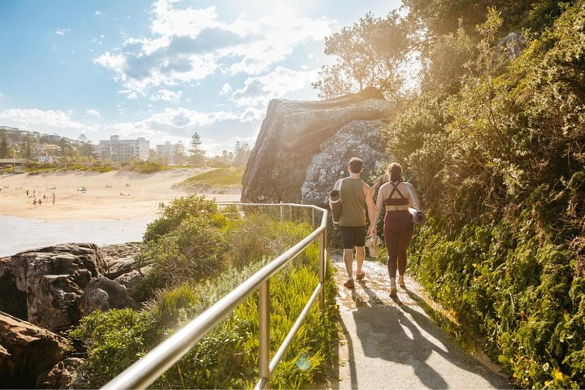 um homem e uma mulher caminhando por um caminho perto da praia