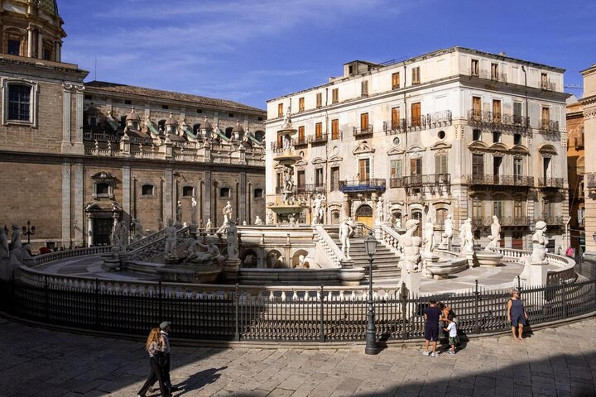 people walking around a fountain in front of a building