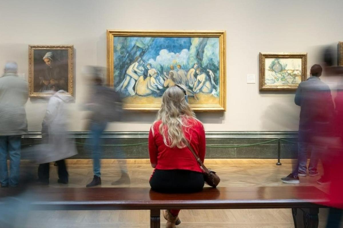 seorang wanita duduk di bangku di museum seni