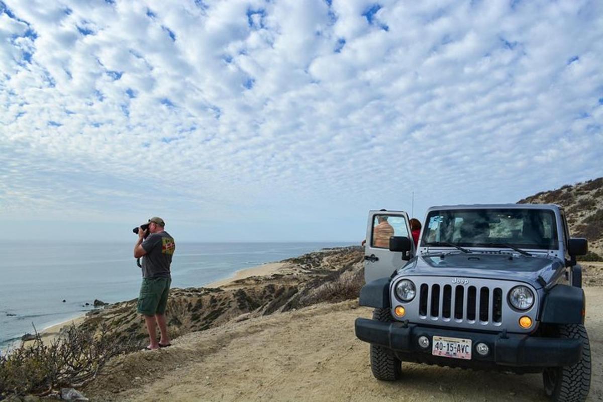 um homem tirando uma foto de um jipe na praia