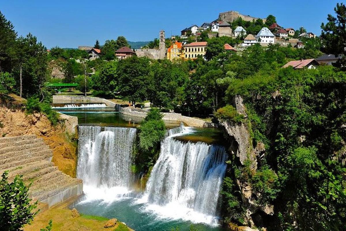 una cascata in un fiume con una città sullo sfondo