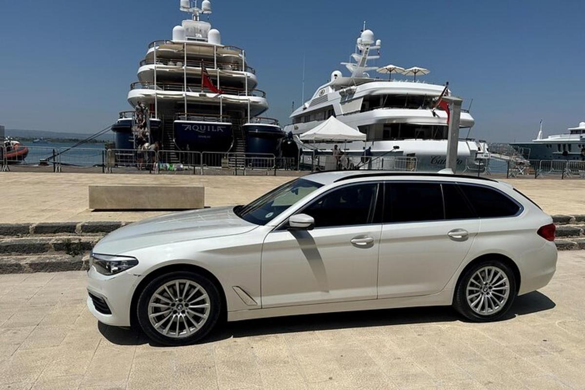 Un coche blanco aparcado delante de un barco.