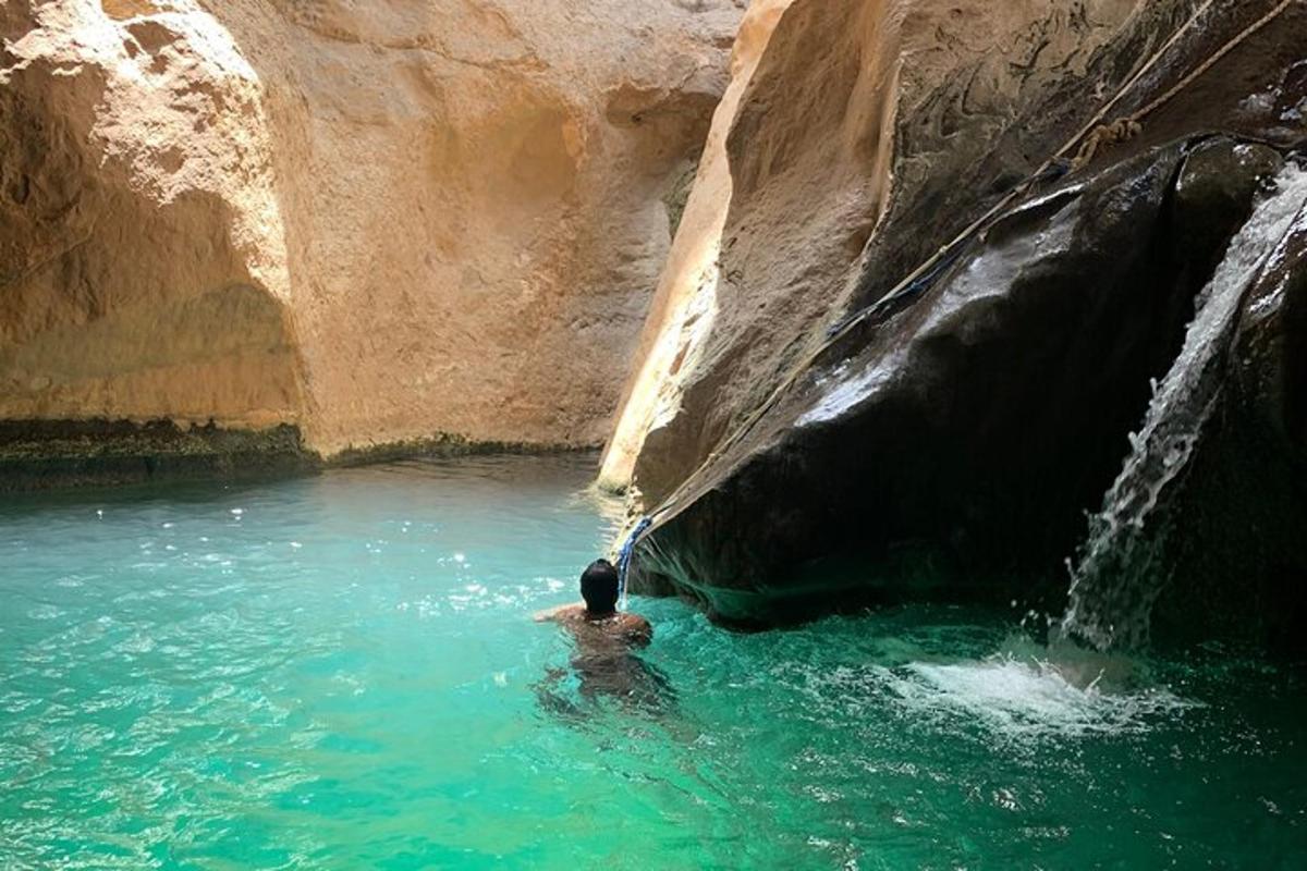رجل في بركة ماء بجوار شلال