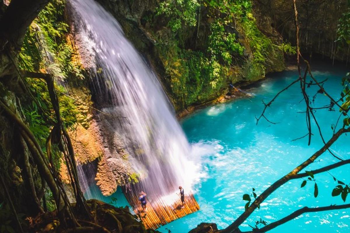 una cascata nella giungla con persone in piedi nell'acqua