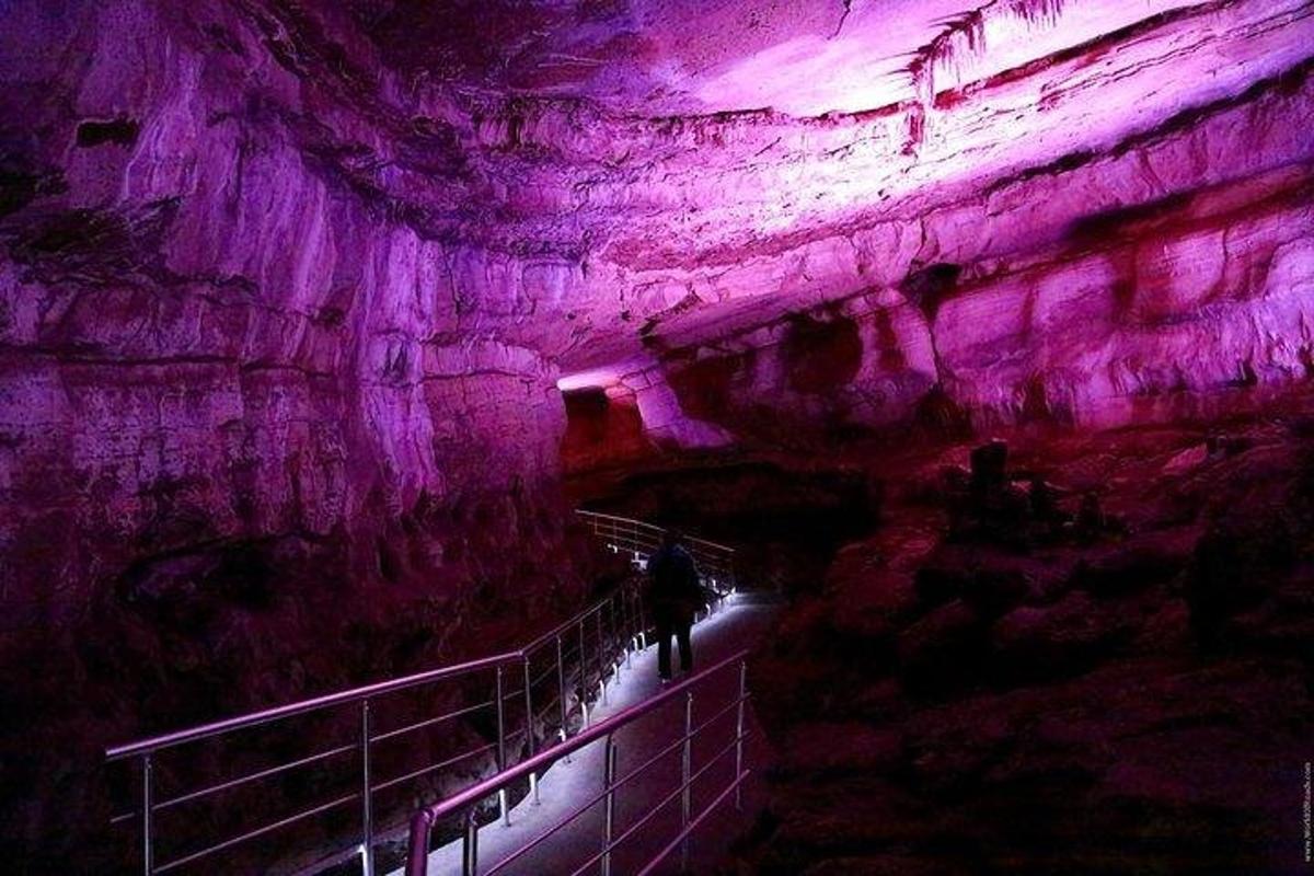 Una persona caminando por una cueva con iluminación violeta.