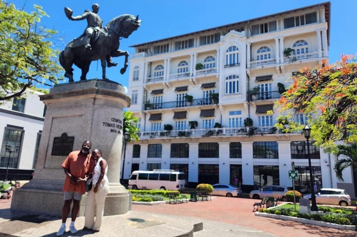 una coppia in posa davanti a una statua di fronte a un edificio