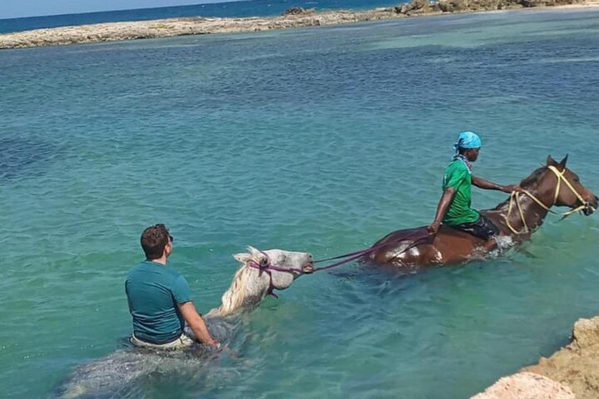 due persone a cavallo in acqua con un cane