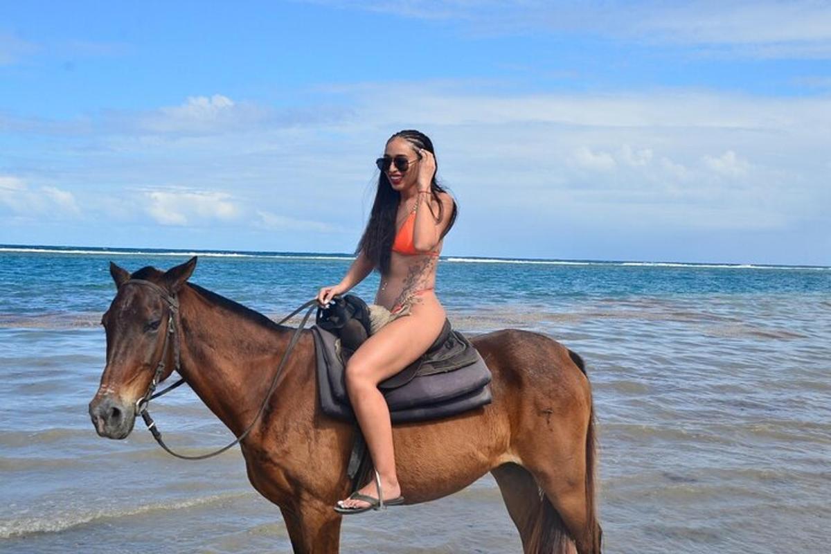 ženska v bikiniju jaha konja na plaži