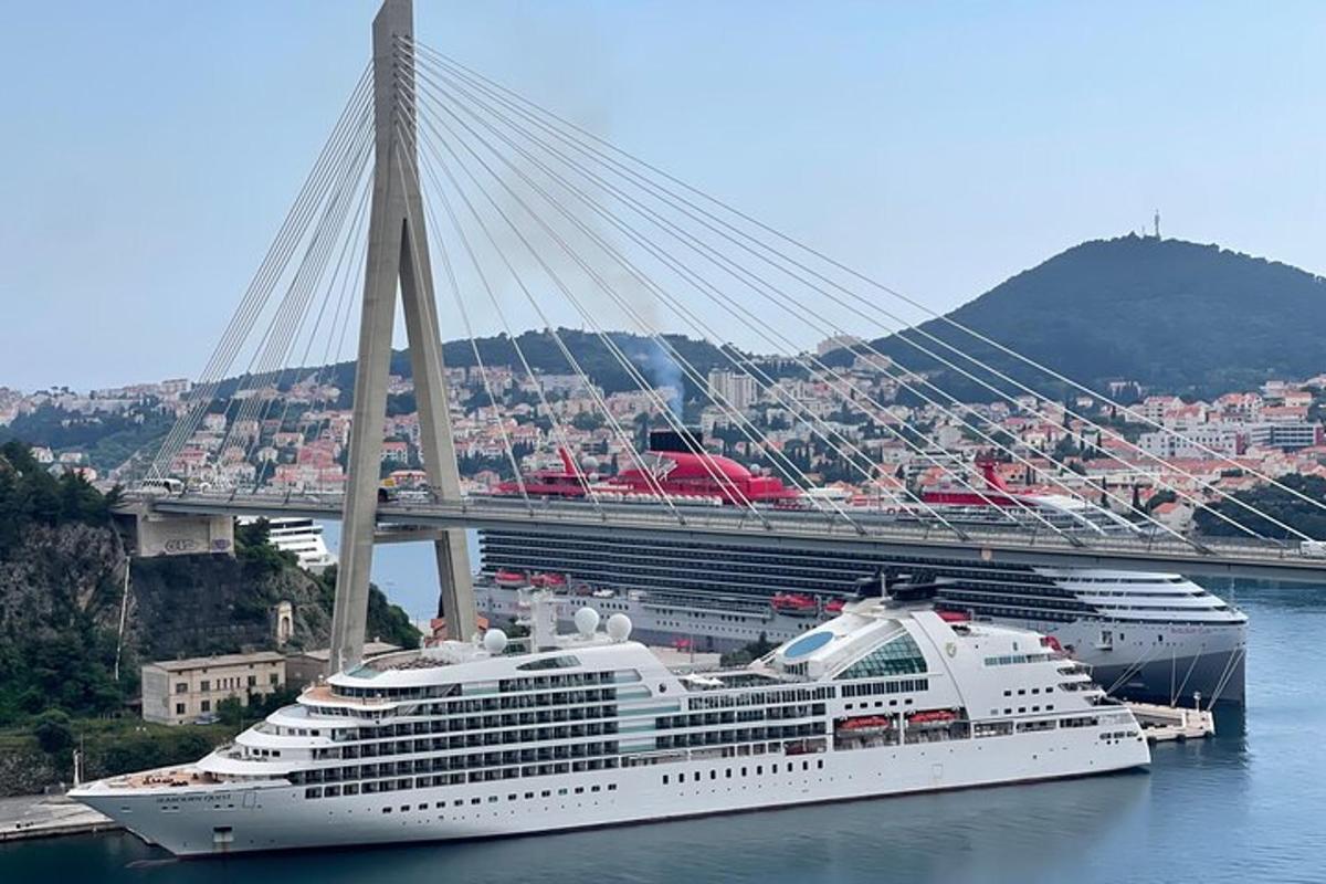 a cruise ship in the water with a bridge in the background
