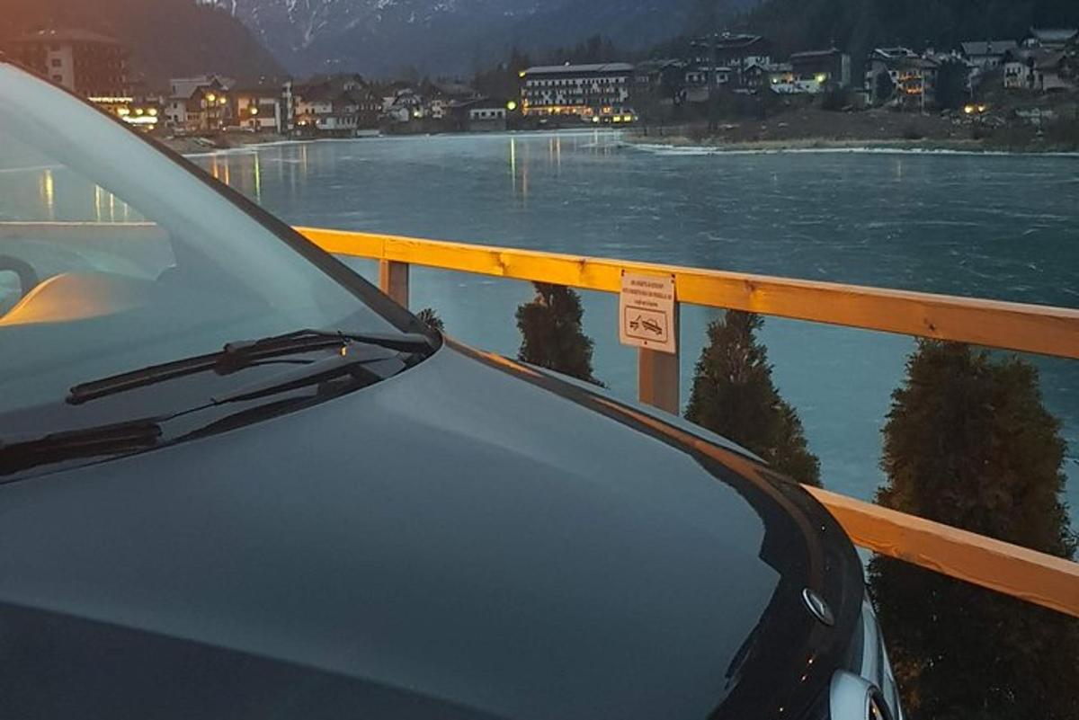 un'auto parcheggiata su un ponte con uno specchio d'acqua