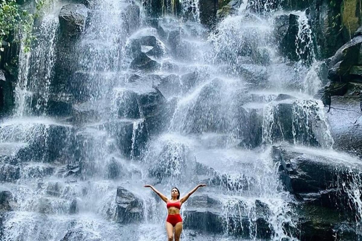 seorang wanita berdiri di hadapan air terjun