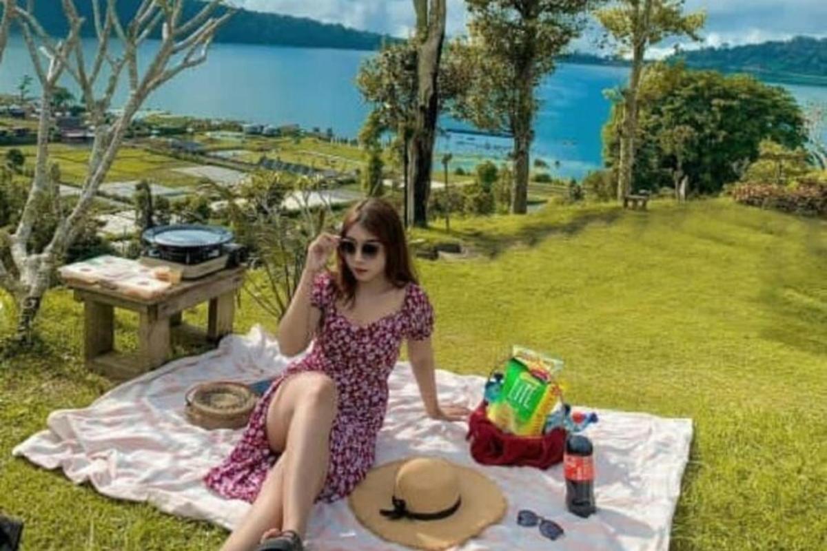 en ung kvinde sidder på et picnictæppe