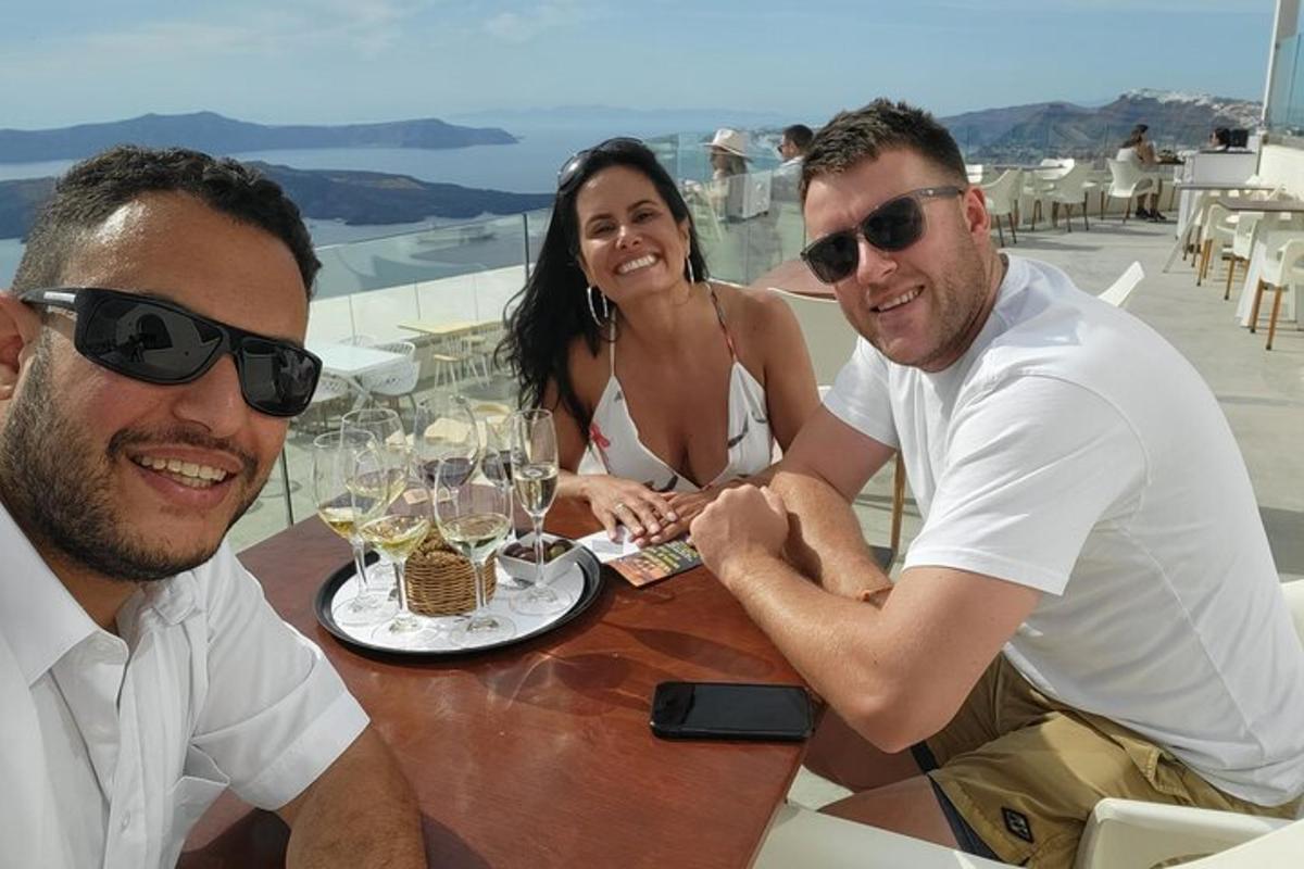 Δύο άνδρες και μια γυναίκα κάθονται σε ένα τραπέζι με ποτήρια κρασιού