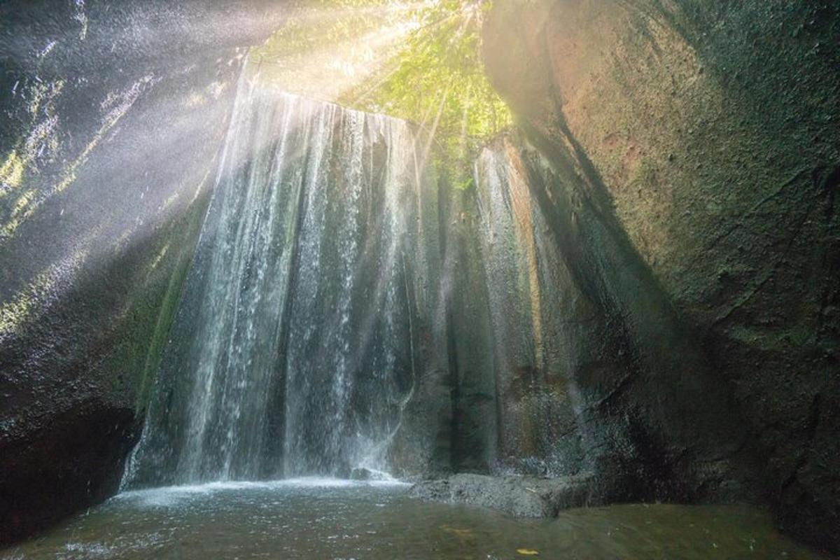Una cascada en una cueva con el sol brillando sobre ella.