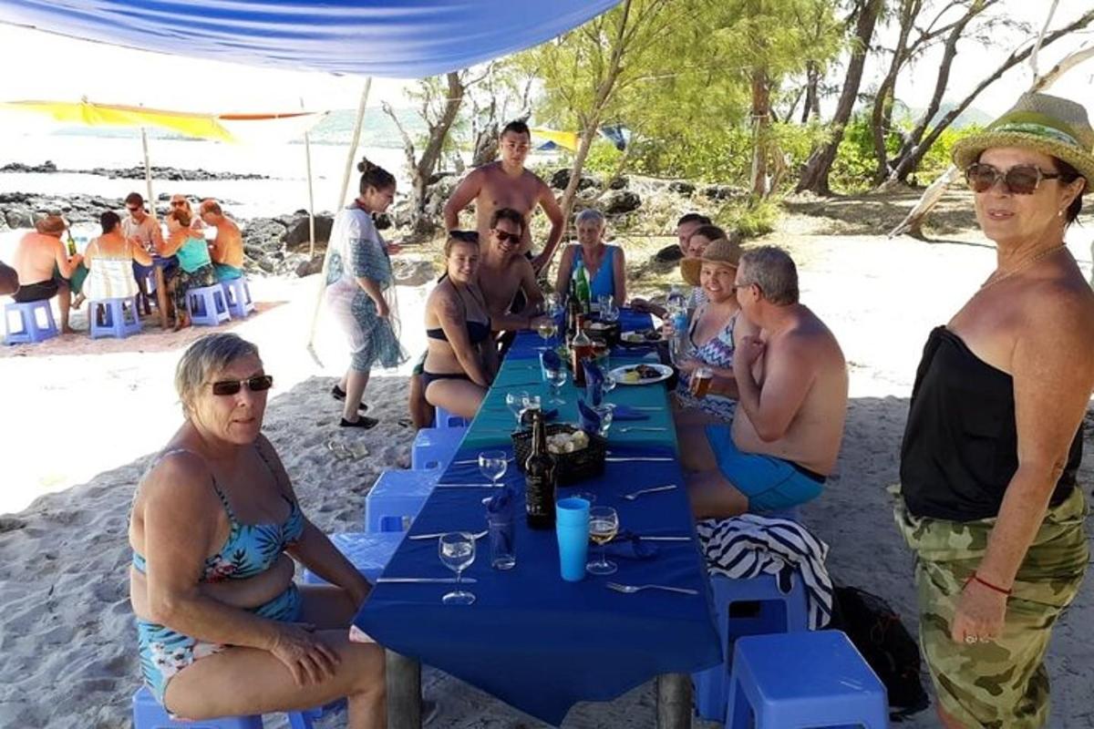 en grupp människor som sitter vid ett bord på stranden