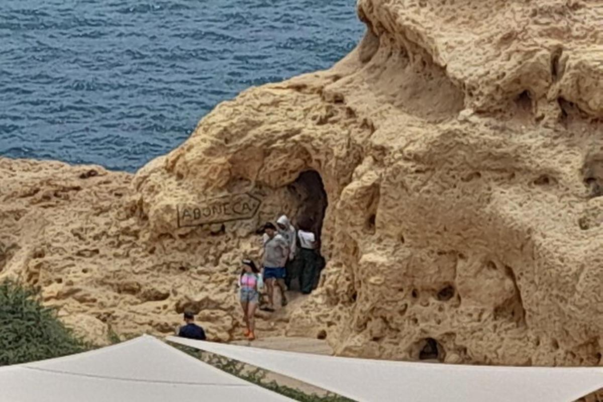 μια ομάδα ανθρώπων που βγαίνει από μια σπηλιά σε έναν γκρεμό