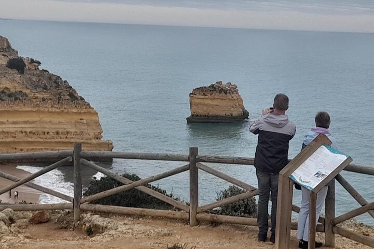 Δύο άνθρωποι στέκονται σε έναν φράχτη κοιτάζοντας τον ωκεανό