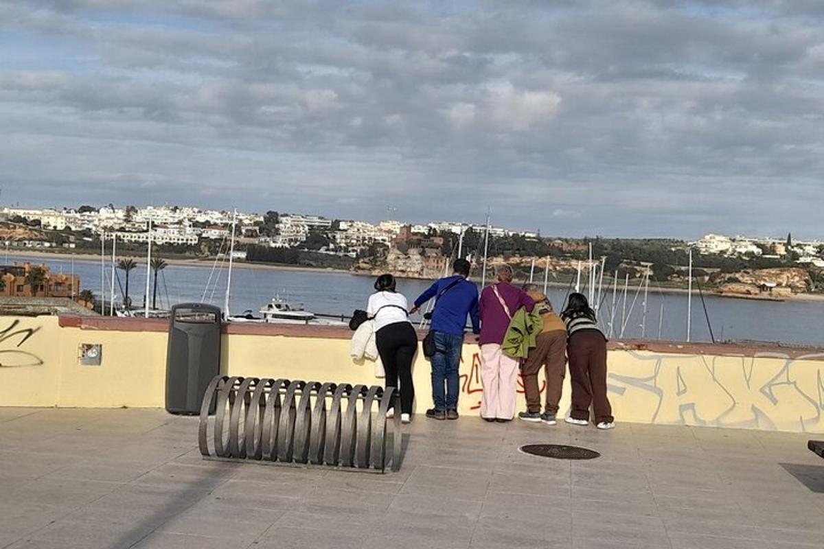 μια ομάδα ανθρώπων που στέκονται σε έναν τοίχο κοιτάζοντας το νερό